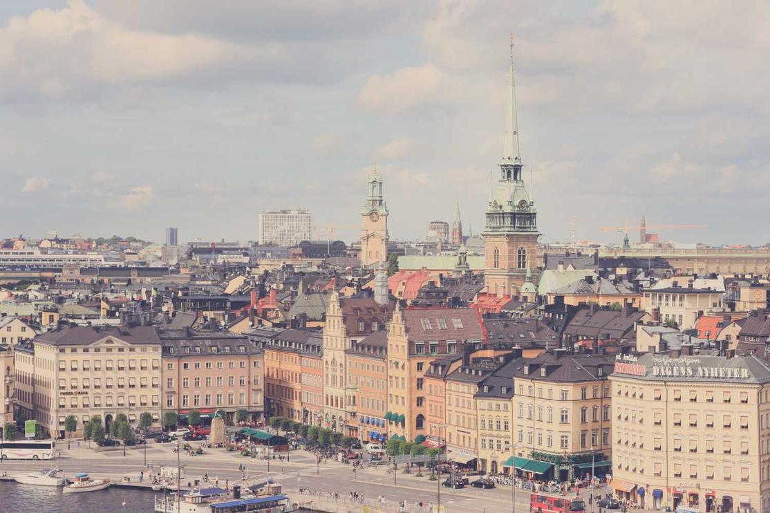 A scenic view of a European city with historic buildings, church spires, and cloudy skies above.